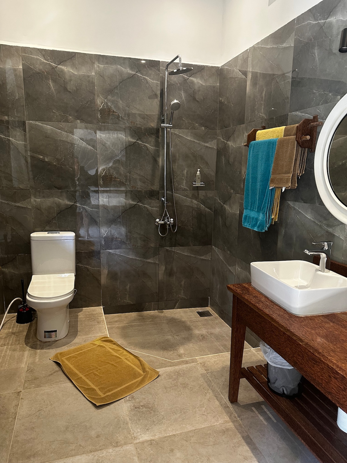 En-suite bathroom with dark grey marble tiles, walk-in shower and wooden vanity
